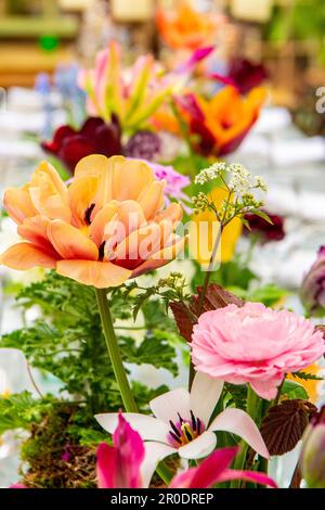 Eine wunderschöne Blumenausstellung, die bei einer Hochzeit in der Mitte eines Tisches verläuft Stockfoto