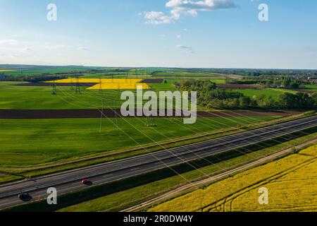 Luftaufnahme eines Strompylons mit Stromleitungen über dem landwirtschaftlichen Feld. Stockfoto