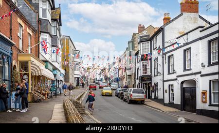 Am 7. Mai 2023 in Lyme Regis, Dorset, Großbritannien, blickt ihr auf die Broad Street, die mit farbenfrohen Bunts und Union Jack Flags dekoriert ist Stockfoto