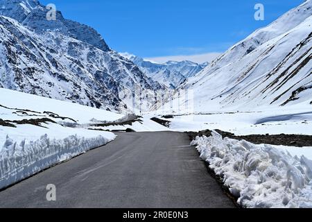 Die Straße in der Nähe des Pfeilschilds verschwindet in schneebedeckter Landschaft Stockfoto