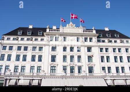 Kopenhagen, Dänemark - 6. April 2023: Weiße Fassade des Hotel d'Angleterre mit dänischen Flaggen oben im Zentrum von Copenhegen mit klarem blauem Himmel Stockfoto