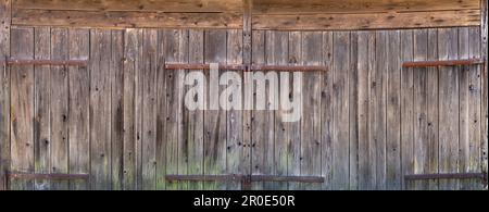 Zwei alte verwitterte Holzgaragentüren nebeneinander mit großen Scharnieren Stockfoto