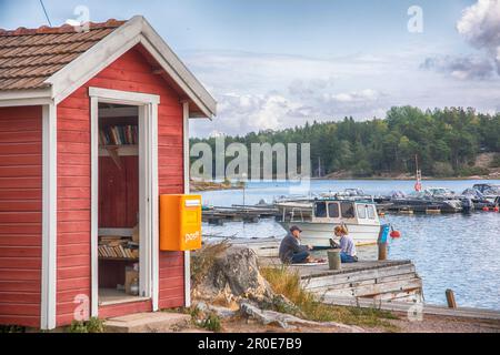 Ein Fischerhaus und ein Paar, das ein Picknick auf einer Anlegestelle macht, Korpo Island, Westküste Finnlands Stockfoto