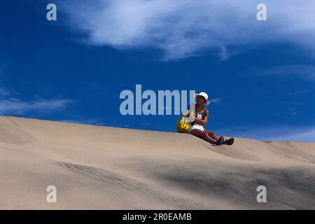 Frau sitzt auf den Sanddünen, Playa del Ingles, Maspalomas, Gran Canaria, Kanarische Inseln, Spanien Stockfoto