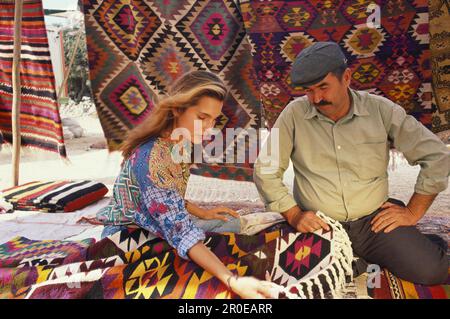 Tourist und Verkäufer an einem Marktstand mit Teppichen, Bodrum, Türkei, Europa Stockfoto