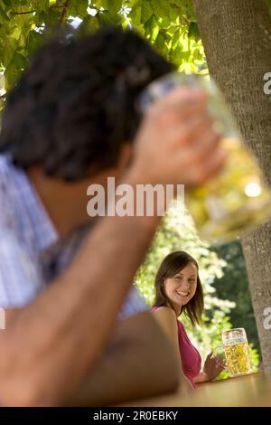 Zwei junge Leute, die sich im Biergarten anlächeln, München, Bayern Stockfoto