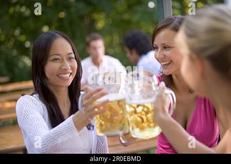 Drei junge Frauen, Freunde, die Spaß in einem Biergarten haben, See Starnberg See, Bayern, Deutschland Stockfoto
