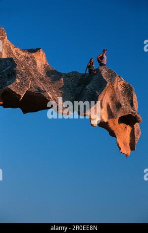 Zwei Wanderer auf einem Felsvorsprung bei Capo d'Orso, einem bärförmigen Felsen, Sardinien, Italien Stockfoto