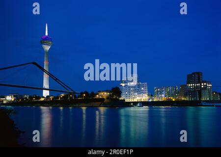 Beleuchtete Gebäude des Medienhafens bei Nacht mit Rheinturm und Neuer Zollhof, Düsseldorf, Nordrhein-Westfalen Stockfoto