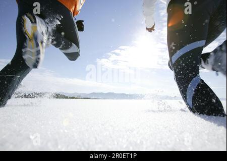 Ein junges Paar, das durch Pulverschnee läuft Stockfoto