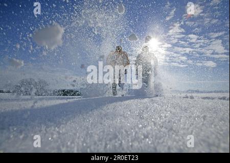 Ein junges Paar, das durch Pulverschnee läuft Stockfoto