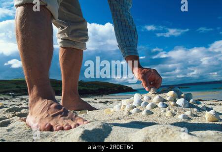 Ein Mann sucht Muscheln an einem Strand, Herm, Kanalinseln, Großbritannien Stockfoto