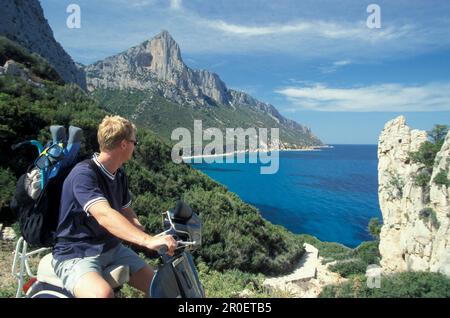 Mann auf einer Vespa und genießt die Aussicht, Punta Pedra Longa, Baunei, Sardinien, Italien Stockfoto