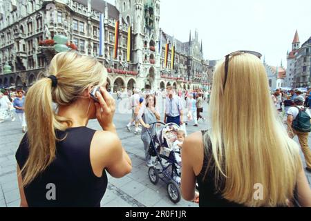Zwei junge Frauen mit Mobiltelefonen, Marienplatz, München Stockfoto