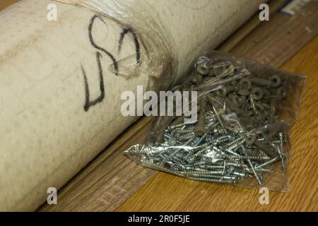 Auf dem Boden liegt eine Folienverpackung mit selbstschneidenden Schrauben Stockfoto