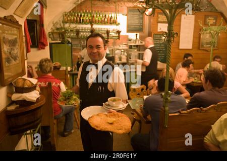 Der Kellner serviert Wiener Schnitzel im Restaurant Figlmueller, Wien, Österreich Stockfoto