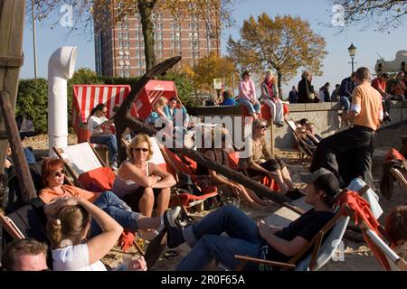 Leute sitzen auf Liegestühlen im Museumshafen, Leute sitzen auf Liegestühlen eines Open-Air-Cafés am Sandstrand des Museumshafen oevelgoenne, Hamburg, Stockfoto