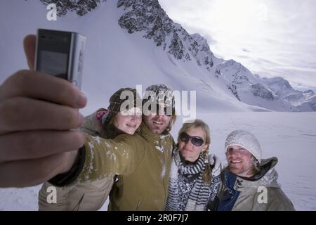 Vier junge Skifahrer, die sich mit einem Kameratelefon fotografieren, Kuehtai, Tirol, Österreich Stockfoto