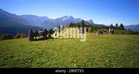 Wanderer auf Bank, Graseck, Blick auf Wetterstein und Zugspitze, Alpspitze, Oberbayern, Deutschland, Alpspitze Stockfoto