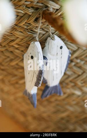 Holzfische, die an einem Strohkorb hängen Stockfoto