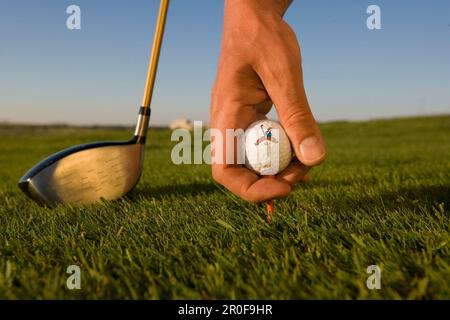 Golf, Mann legt Golfball auf das T-Shirt Stockfoto