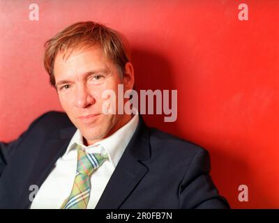 Geschäftsmann lehnt sich an die rote Wand, Porträt Stockfoto