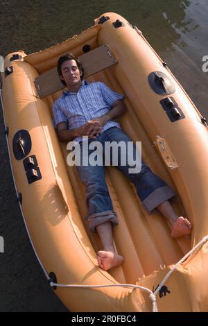 Junger Mann liegt im Schlauchboot Stockfoto