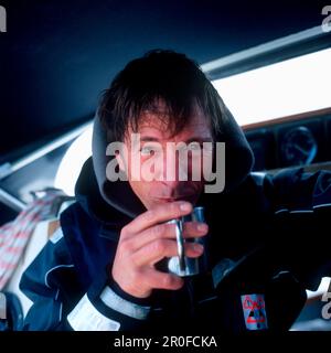 Porträt eines Mannes auf einem Segelboot, der eine Tasse heißen Kaffee trinkt, in der Bucht von Kiel zwischen Deutschland und Dänemark Stockfoto