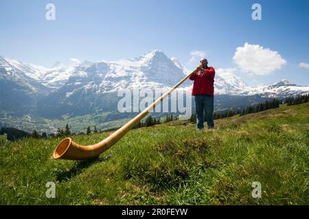 Ein Mann spielt ein Alphorn in Bussalp 1800 m, Grindelwald, Berner Oberland, Kanton Bern, Schweiz Stockfoto