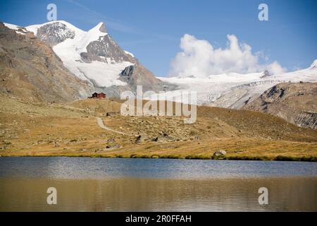 Blick über das Stellisee (2537 m) bis zur Alpenhütte Fluhalp mit schneebedeckten Alpen im Hintergrund, Zermatt, Wallis, Schweiz Stockfoto