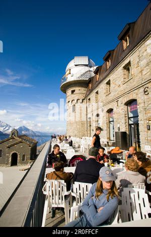 Gäste sitzen auf der Terrasse des Kulmhotel Restaurants, dem höchsten Hotel in den Schweizer Alpen (3100 m) in Gornergrat, Zermatt, Wallis, Schweiz Stockfoto