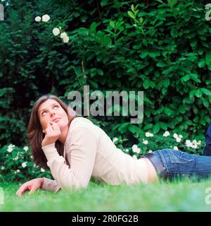 Mittelgroße Erwachsene Frau, die auf dem Gras liegt Stockfoto