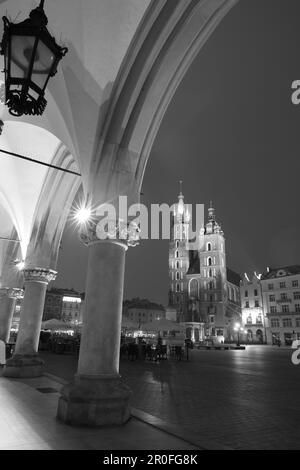 Schwarzweißbild der Basilika St. Marys aus den Bögen der Tuchhalle. Krakau, Polen, Europa. Stockfoto