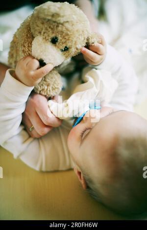Baby spielt mit Teddybär Stockfoto