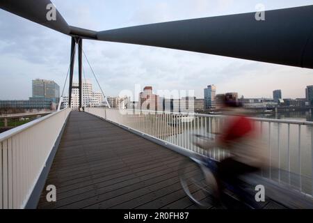 Radfahrer auf der Fußgängerbrücke im Media Harbour in Düsseldorf, Landeshauptstadt von NRW, Nordrhein-Westfalen Stockfoto