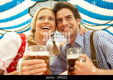 Lachendes Paar mit einem Liter Bier in einem Bierzelt Stockfoto