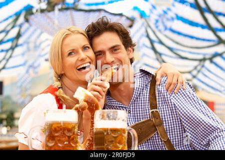 Paar mit Bier und Brezel in einem Bierzelt Stockfoto