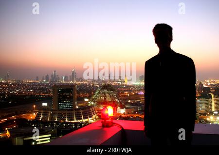 Mann beobachtet Dubai in der Abenddämmerung vom Dach des Grand Hyatt Hotels, Dubai, Vereinigte Arabische Emirate, VAE Stockfoto