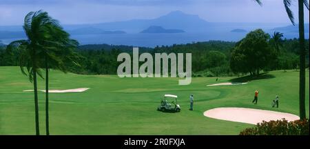 Leute auf dem Golfplatz des Tagaytay Country Club mit Taal Volcano, Tagaytay, Luzon Island, Philippinen, Asien Stockfoto