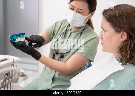 Zahnärztin in Schutzmaske und Handschuhen mit Patient in der Zahnklinik. Stockfoto