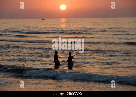 Zwei Menschen stehen im Meer und fischen in der Dämmerung, Musandam, Oman, Asien Stockfoto