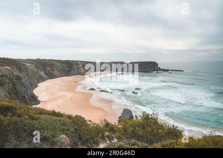 Der berühmte Strand Praia dos Machados in Odemira, westlich von Portugal. Die Felsen rund um den mondförmigen Sandstrand mit großen Wellen aus dem Atlantik Stockfoto