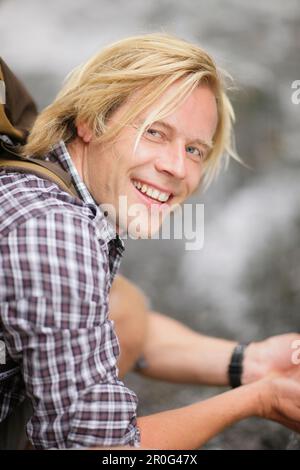 Junger Mann, der vom Wasserfall trinkt, Werdenfelser Land, Bayern, Deutschland Stockfoto