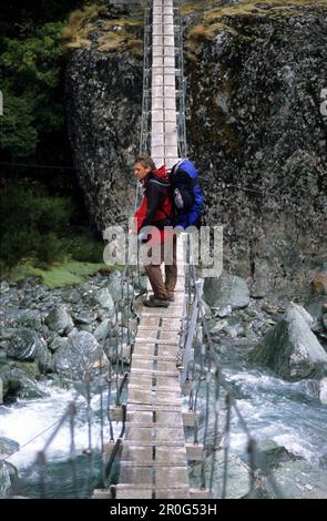 Mann auf einer Hängebrücke über die Rees Dart River, Mount Aspiring Nationalpark, Südinsel, Neuseeland, Ozeanien Stockfoto