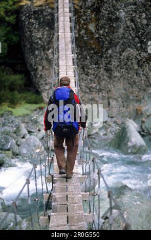 Mann auf einer Hängebrücke über die Rees Dart River, Mount Aspiring Nationalpark, Südinsel, Neuseeland, Ozeanien Stockfoto