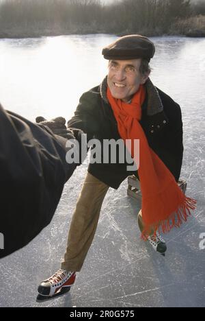 Person, die Eiskunstläuferin beim Aufstehen hilft, Ammersee, Oberbayern, Deutschland Stockfoto