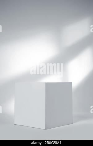 Minimale Produktanzeige, weißer Würfel auf weißem Hintergrund und Fensterbeleuchtung. Podium-Sockelszene, Ausstellungsplattform Stockfoto