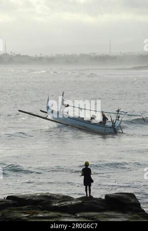 Fischerboot auf dem Wasser und Angler auf einem Felsen, Pekutatan, Bali, Indonesien, Asien Stockfoto