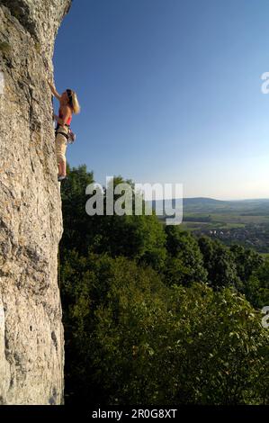 Frau Klettern auf einer Felswand in der Sonne, Fränkische Schweiz, Bayern, Deutschland, Europa Stockfoto