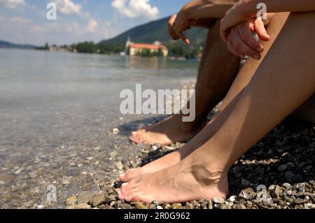 Zwei Personen Baden ihre Füße in das Wasser mit einem See, See Tegernsee, obere Bayern, Bayern, Deutschland Stockfoto